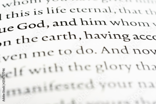 A macro shot of a page portion of the biblical text with selective focus on the word  God. 