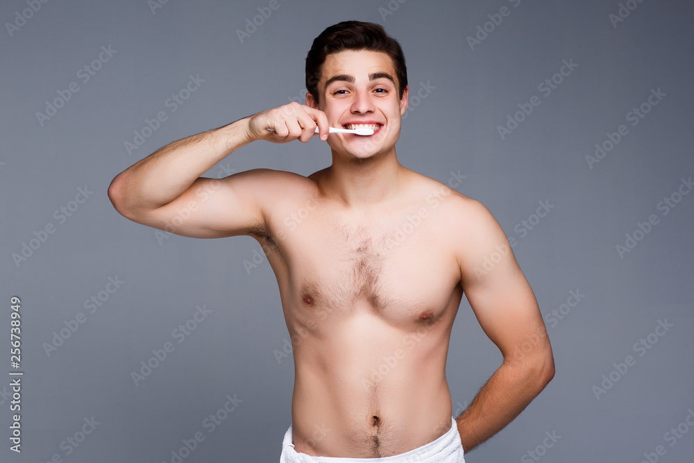 Fototapeta premium Young man brushing his teeth. Man brushing teeth isolated on gray!