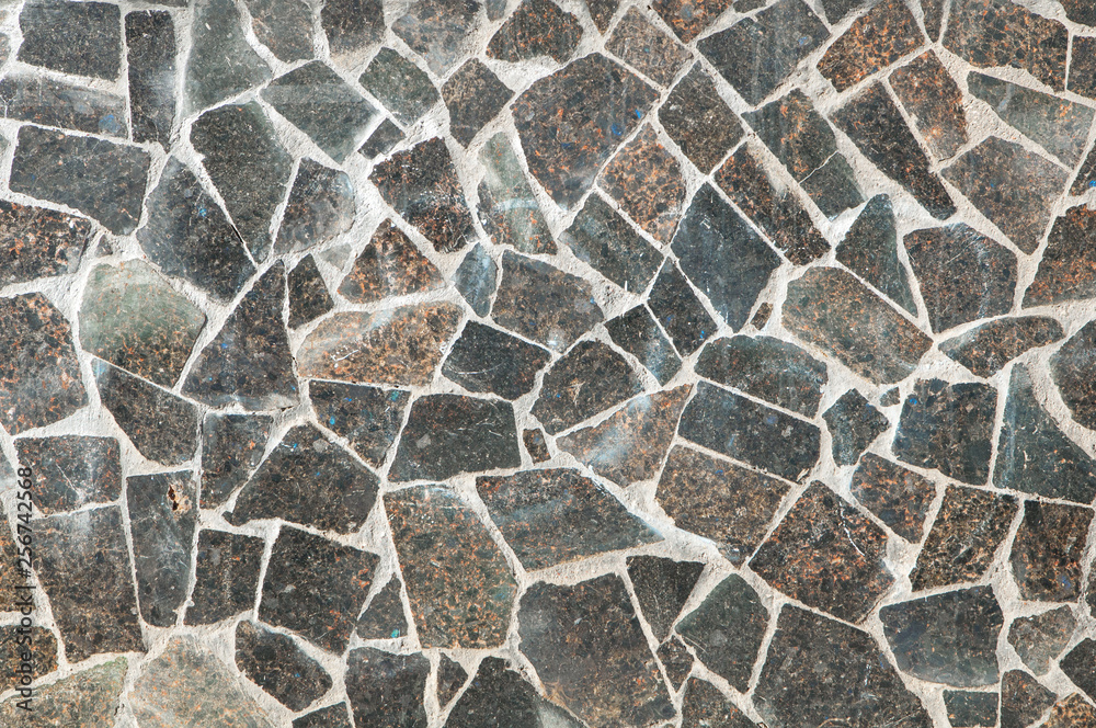 Mosaic wall granite pieces of building in sunny day. Pieces of marble bonded with gray cement. Mosaic wall granite pieces of building in sunny day. Pieces of marble bonded with gray cement.