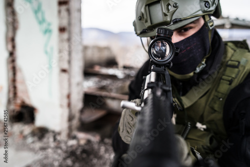 Young Special forces SWAT soldier aiming with assault rifle gun at the ruined building war terrorist battle zone