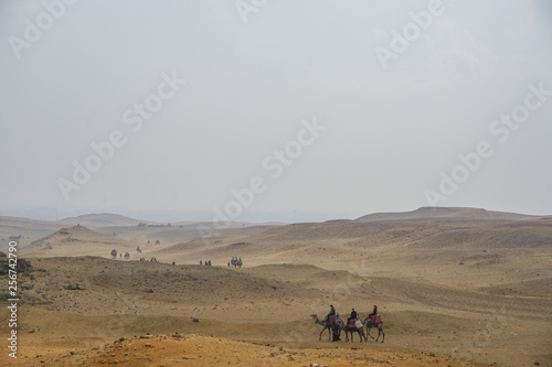 Giza, Egypt: Tourists ride camels on the sand near the Khufu Pyramid Complex.