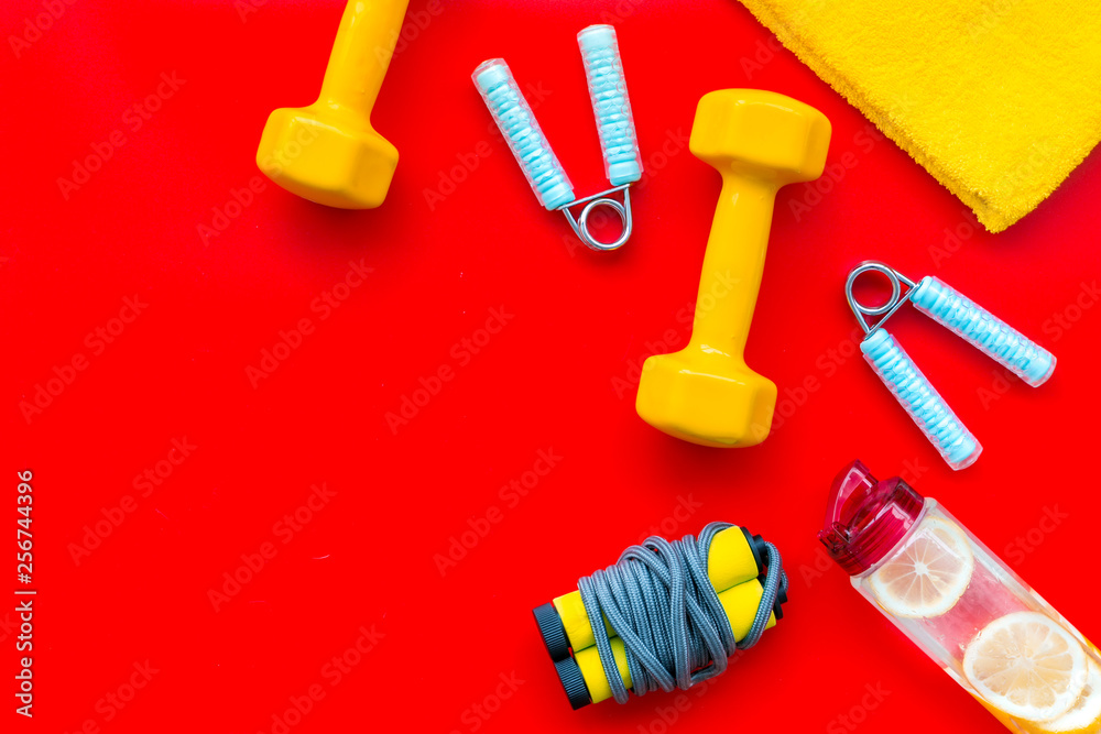 Fitness background with sport equipment for gym and home on red background top view copyspace Fitness background with sport equipment for gym and home on red background top view copyspace