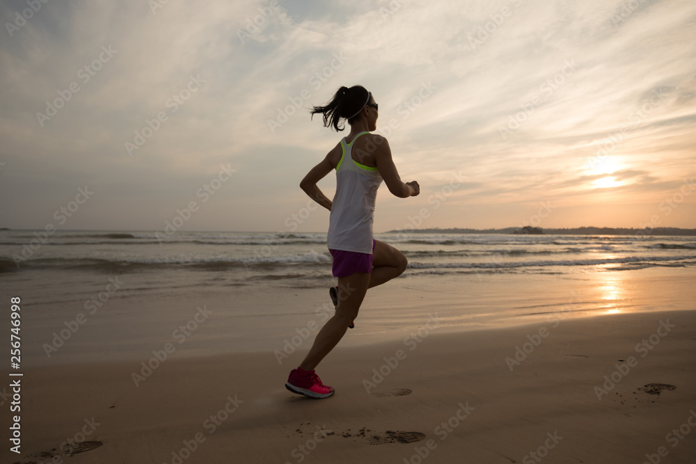 Woman runner running on sunset beach
