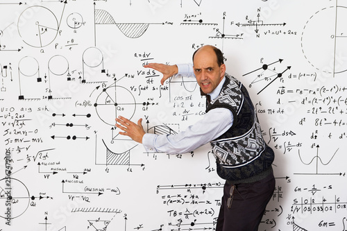 Vászonkép Middle aged caucasian mathematician explaining equations on a white wall