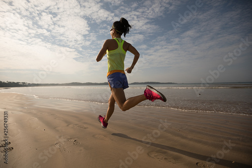young fitness woman running at sunrise beach 