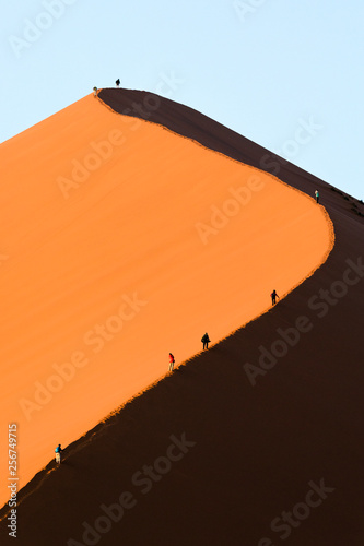 Fototapeta Naklejka Na Ścianę i Meble -  Tourists climb a red sand dune