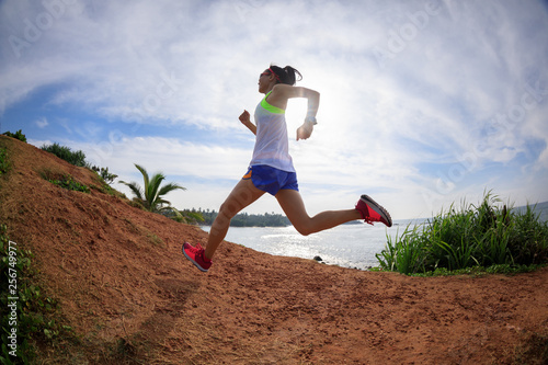 Woman trail runner running on seaside hills