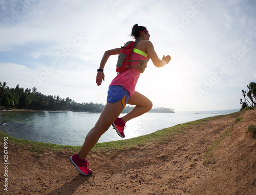 Woman trail runner running on seaside hills © lzf