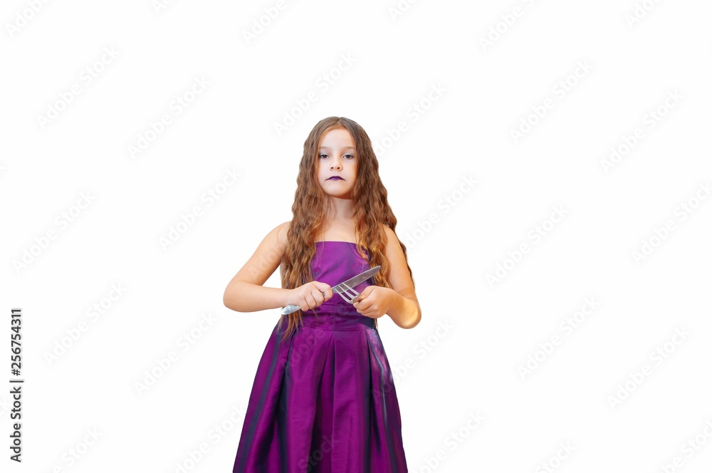 Beautiful little girl with long hair in evening dress, portrait emotionally posing with a knife and fork, isolated