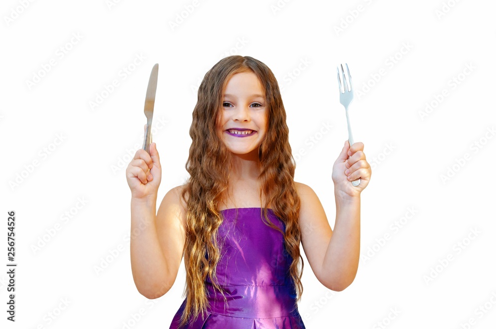 Beautiful little girl with long hair in evening dress, portrait emotionally posing with a knife and fork, isolated Beautiful little girl with long hair in evening dress, portrait emotionally posing with a knife and fork, isolated