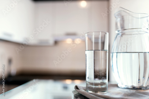 A glass of fresh water with crafin on the background of a modern kitchen.