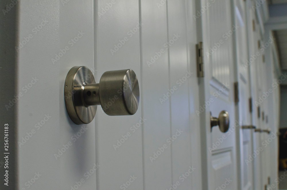 A low view of the round silver style handles along the wall of doors in the store. A low view of the round silver style handles along the wall of doors in the store.
