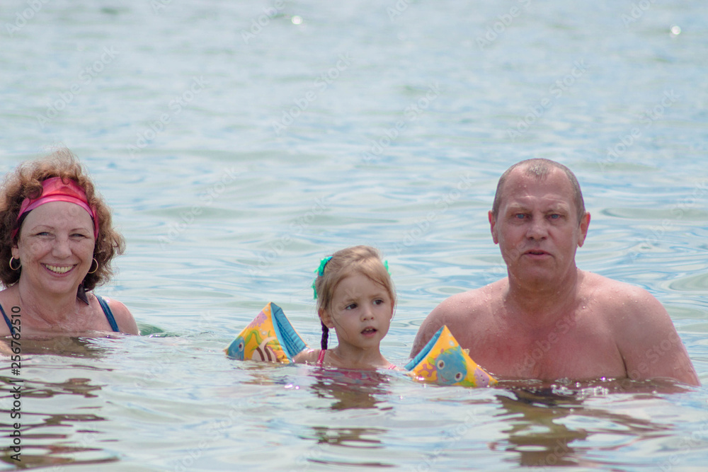 Grandparents And Granddaughter swimming in the sea, they smile and happyness