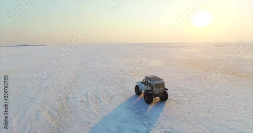 Beautiful aerial view of swamp buggy with big wheels driving on ice of big frozen lake Hanka in Russia. Evening photo