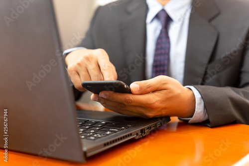 Businessman using cell phone and work on laptop.
