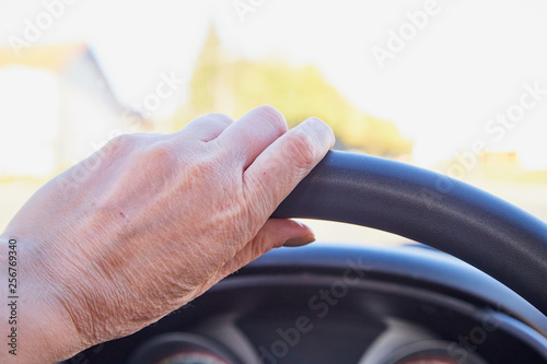 Female hands on the steering wheel of a car while driving and road background