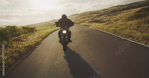 Motorcyclist riding fast at sunset on country road, motorcycle adventure lifestyle photo