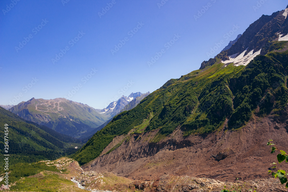 Alpine river in the valley of mountains in the surroundings of Dombai. Caucasus Mountains summer, clear day from the forest.