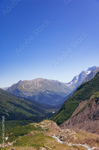 Alpine river in the valley of mountains in the surroundings of Dombai. Caucasus Mountains summer, clear day from the forest.