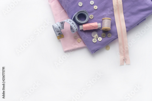 Sewing accessories and fabric on a white background. Fabric, sewing threads, needles, buttons, zipper and sewing centimeter. top view, flatlay