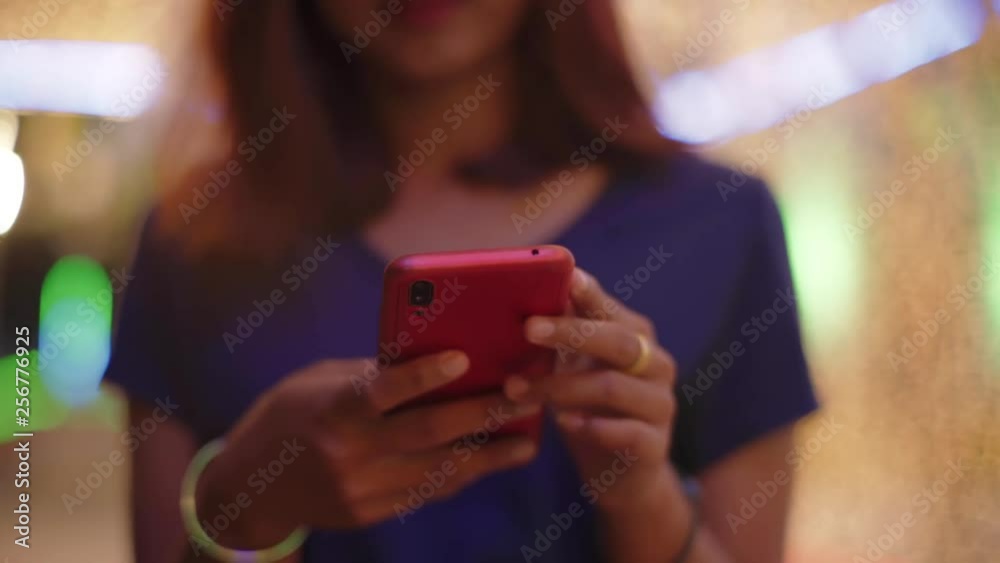 Isolated asian girl hands using smartphone with bright colorful bokeh background night time Isolated asian girl hands using smartphone with bright colorful bokeh background night time