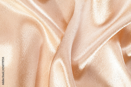 Silk background, texture of beige shiny fabric