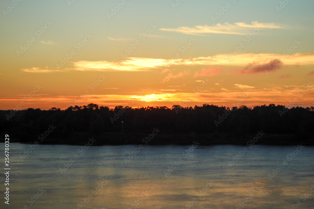 Beautiful deep morning dawn with highlights in the orange rays of the summer sun on a river Volga. Toned in orange colour and backlit. Beautiful deep morning dawn with highlights in the orange rays of the summer sun on a river Volga. Toned in orange colour and backlit.