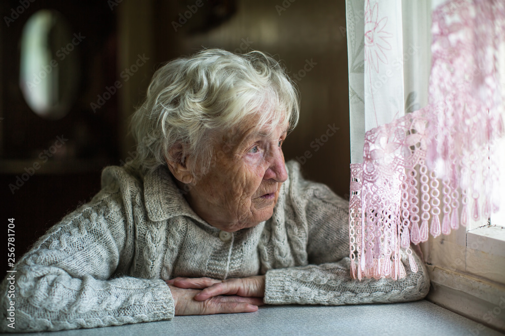 Lonely old ledy elderly woman looks out the window. Lonely old ledy elderly woman looks out the window.
