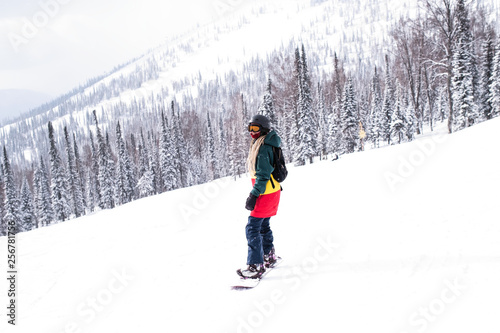 Female snowboarder freerider rides a snowboard on a snowy slope.