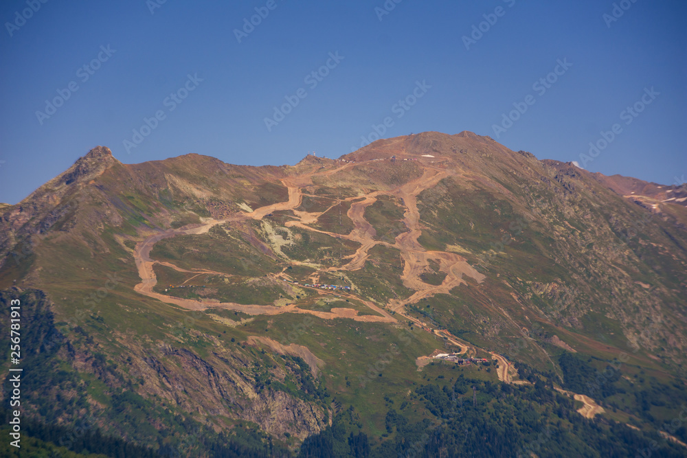 Peaks of mountains in the neighborhood of Dombai. Caucasus Mountains summer, clear day from the forest.