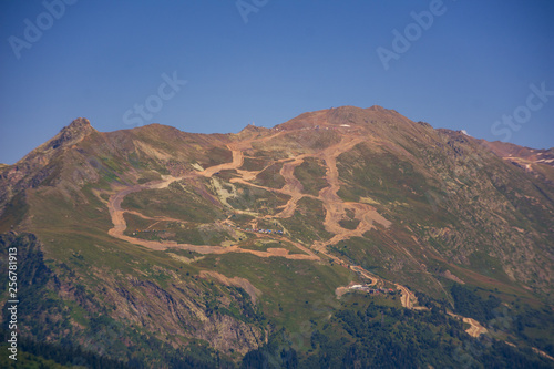 Peaks of mountains in the neighborhood of Dombai. Caucasus Mountains summer  clear day from the forest.