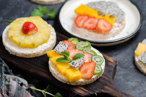 Multigrain rice cakes sandwich with berries, fruit and cream cheese for healthy breakfast.