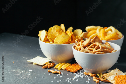 Beer snacks on stone table. Various crackers, potato chips. Top view photo