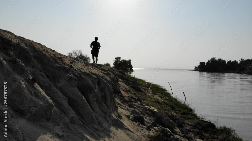 Man walking agianst sunlight on hill from behind Man walking agianst sunlight on hill from behind