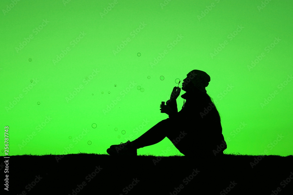 girl blows soap bubbles on a bright green background, trendy background, girl silhouette