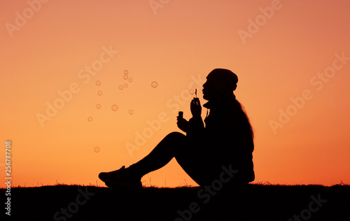 Silhouettes girl at sunset, girl blows bubbles, incredible sunset