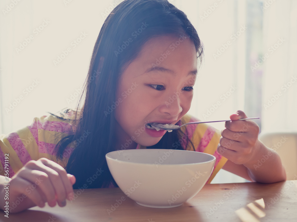 Cute Asian girl eats rice soup for breakfast Cute Asian girl eats rice soup for breakfast