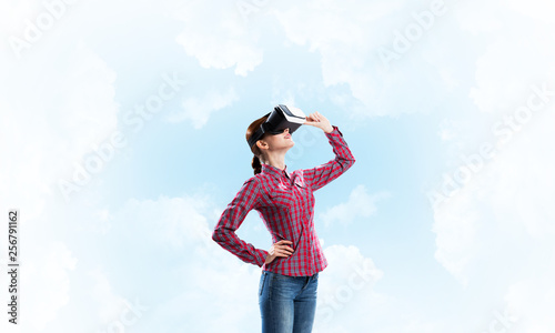 Girl in checked shirt wearing VR glasses experiencing another reality