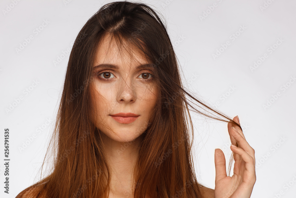 Portrait of a beautiful woman with straight long hair and interesting emotion. Light gray background Portrait of a beautiful woman with straight long hair and interesting emotion. Light gray background