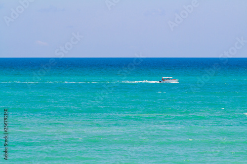 The smooth sea and the small boat with people. Clearly sky in sunshine day.