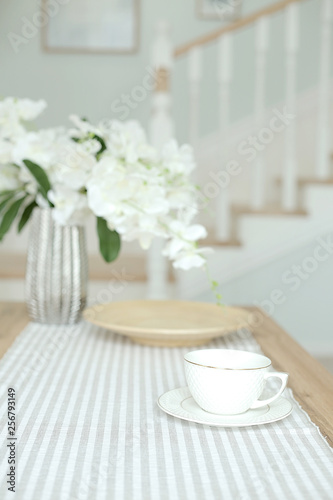 Home interior design. Living room in bright colors. coffee table, white orchids in a glass vase, a cup for coffee. Breakfast concept in a cozy home
