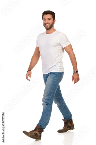 Smiling Man In White T-shirt, Jeans And Boots Is Walking