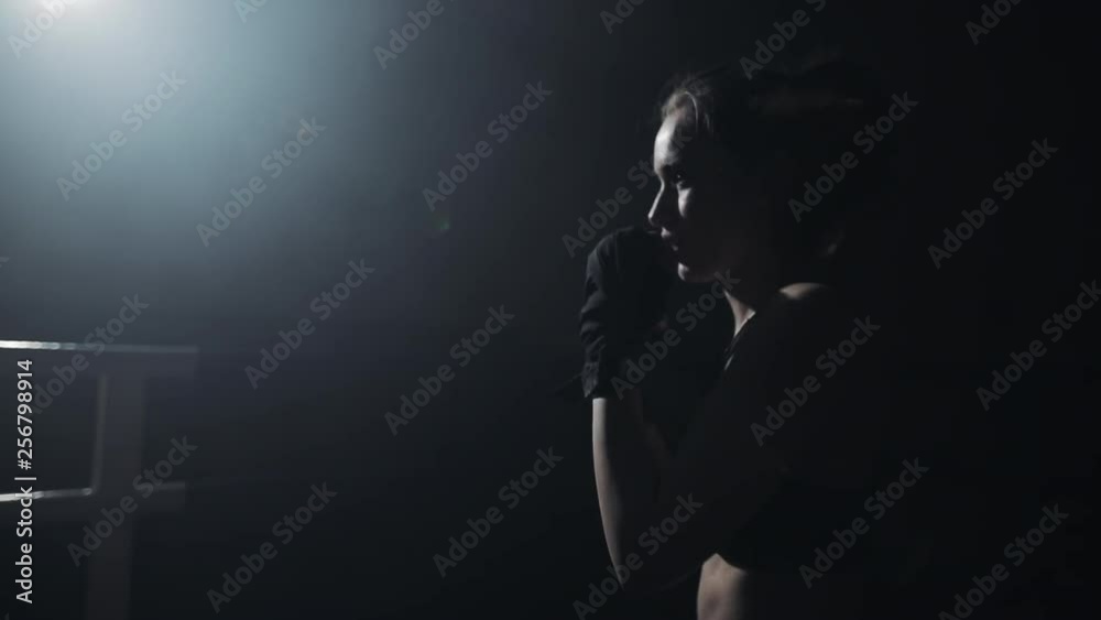Female boxer training in the dark ring. Slow motion. Silhouette. Boxing concept Female boxer training in the dark ring. Slow motion. Silhouette. Boxing concept