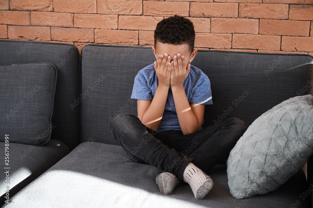 Sad African-American boy crying at home