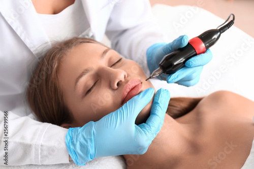 Young woman undergoing procedure of permanent makeup in beauty salon