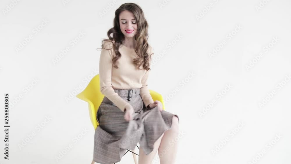 Cute girl sitting on yellow chair posing and smiling, white background Cute girl sitting on yellow chair posing and smiling, white background