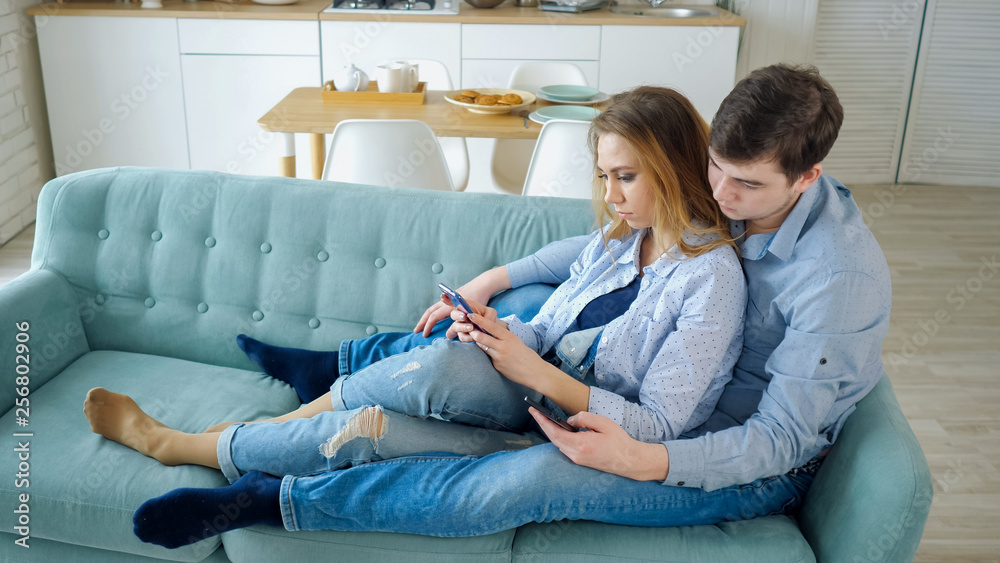 excuus Botsing Conflict guy and girl sit on sofa surfing internet in smartphones, side view Stock  Photo | Adobe Stock