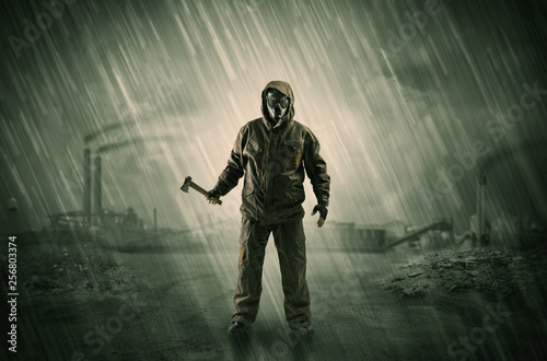 Gas masked survival man coming with arms on his hand  in a demolished dark environment 

