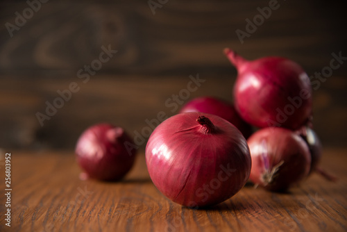 Fresh purple onions on dark wooden background.