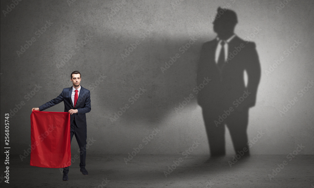 Obraz premium Businessman standing with red cloth on his hand and his shadow on the background 